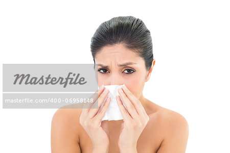 Sick brunette blowing her nose on white background