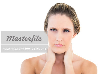 Disgruntled woman looking at camera with a sore neck against white background