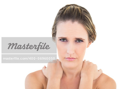 Frowning woman looking at camera with sore shoulders against white background