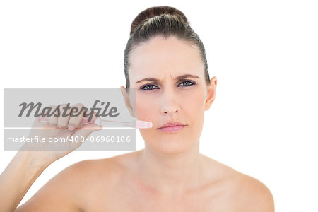 Serious pretty woman brushing her teeth on white background