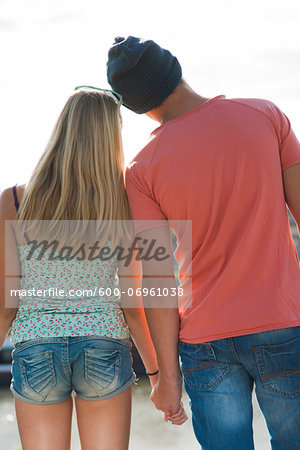 Backview of teenage boy and teenage girl holding hands, standing outdoors, Germany