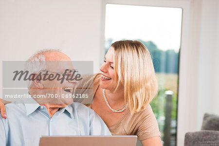 Young Woman and Senior Man Laughing at Home, Mannheim, Baden-Wurttemberg, Germany