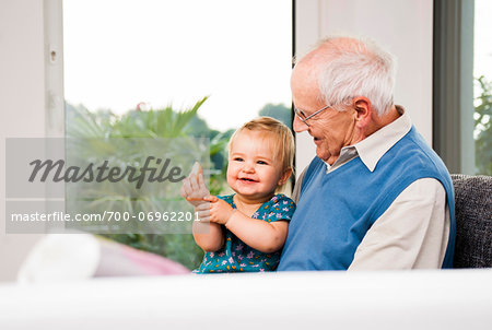 Senior Man with Baby Girl Sitting on his Lap at Home, Mannheim, Baden-Wurttemberg, Germany