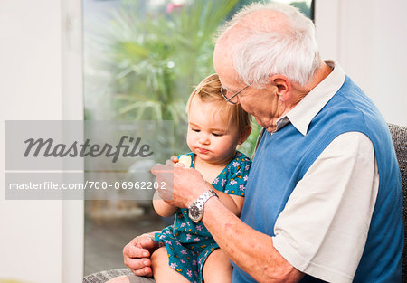 Senior Man with Baby Girl Sitting on his Lap at Home, Mannheim, Baden-Wurttemberg, Germany