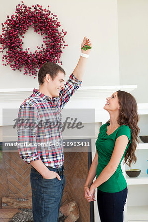 Happy young couple standing in front of fireplace with Christmas decoration
