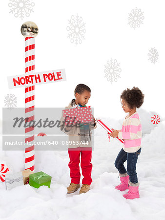 Boy (4-5) and girl (4-5) standing next to North Pole sign