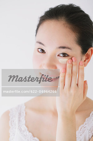 Young woman putting foundation cream