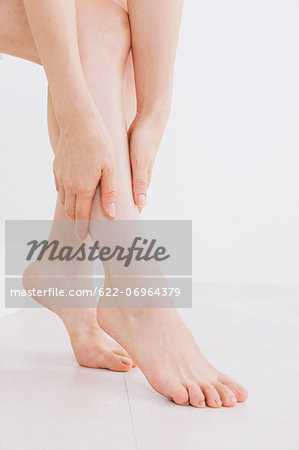 Woman massaging her legs on the floor