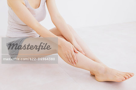 Woman massaging her legs on the floor