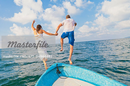 Dressed up man and woman jumping off boat