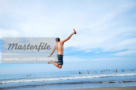 Man leaping in air on beach