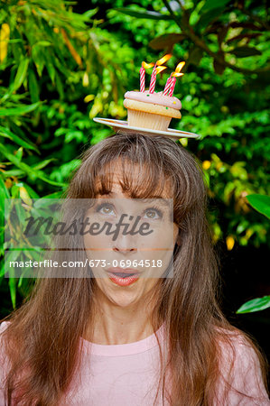 Woman with birthday cupcake on head