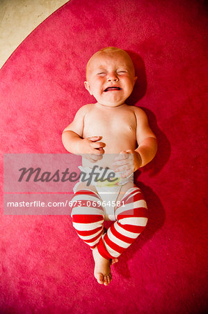 Crying baby on pink rug