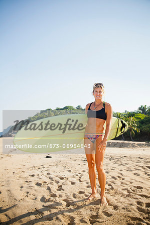 Woman on beach with surfboard