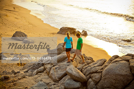 Couple with dog hiking on beach rocks