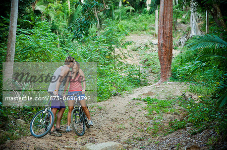 Couple riding bicycles on jungle path