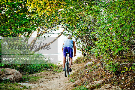 Man riding bicycle on path to beach