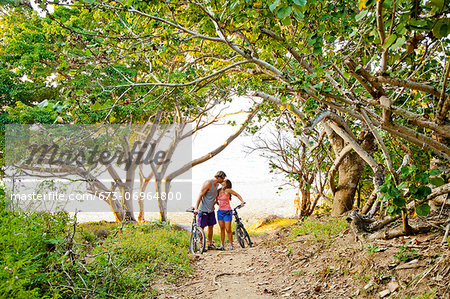 Couple riding bicycles on path to beach