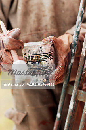 Hands holding can of paint and paintbrush