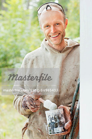 Smiling man holding can of paint