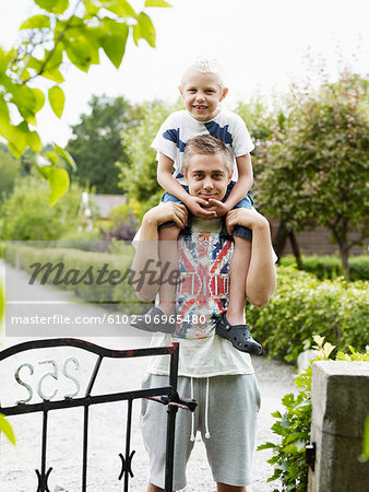 Teenage boy carrying younger brother on shoulders