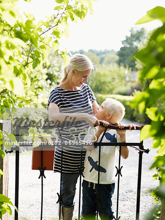 Mother and son standing by garden gate