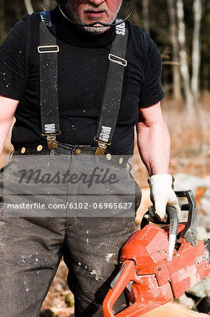 Senior man with chainsaw