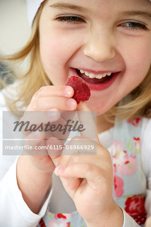 Little girl fooling around with raspberries, Munich, Bavaria, Germany
