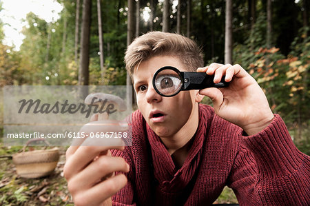 Teenage boy looking at mushroom through magnifying glass, Bavaria, Germany, Europe