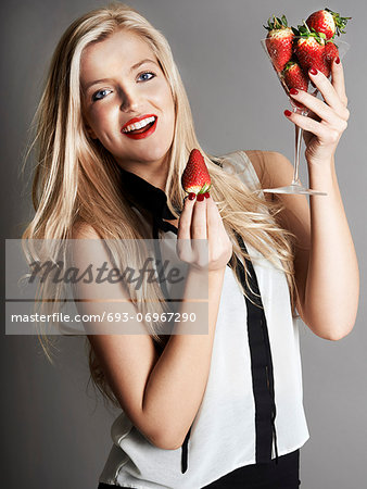 Pretty blonde girl holding glass of Strawberries