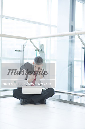 Businessman sitting on floor using laptop