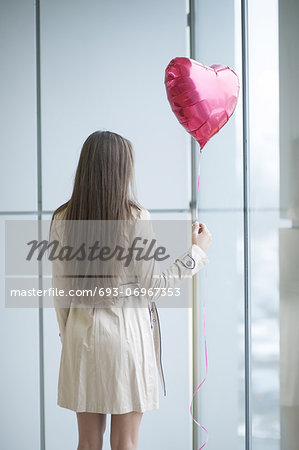 Woman with back to camera holding heart shaped balloon