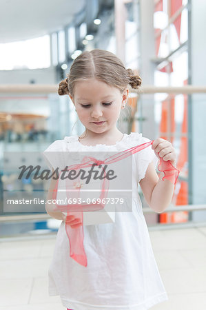 Young girl unwrapping ribbon on present