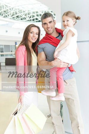 Father and mother pose with young daughter in shopping mall