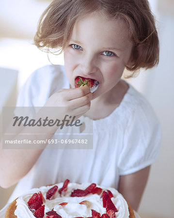 Close-up of Young girl with cake eating strawberry
