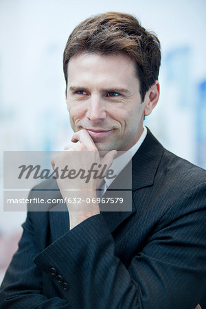 Businessman smiling and looking away in thought, portrait Businessman smiling and looking away in thought, portrait
