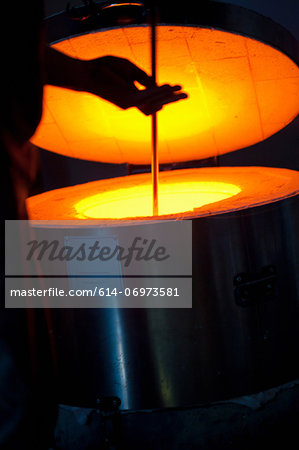 Silhouette of man using furnace in glass factory