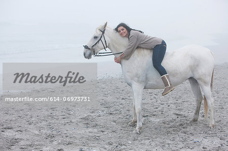 Woman riding horse on beach