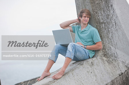 Young man using laptop on pier