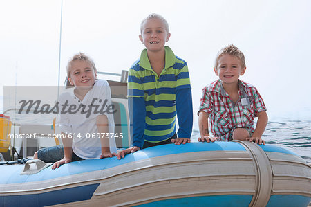 Portrait of three young boys at sea in dinghy
