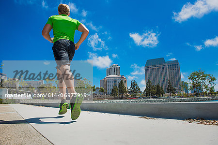 Young man jogging in city, rear view