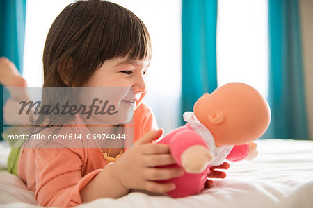 Girl playing with dolly in bedroom