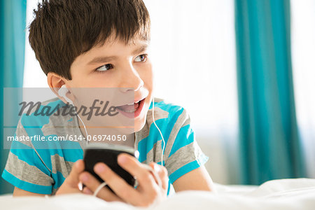 Boy listening to mp3 player on bed