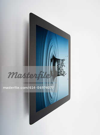 Digital tablet with crown shaped water drop splash on screen Digital tablet with crown shaped water drop splash on screen
