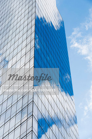 Blue cloudy sky reflected in windows of modern skyscraper