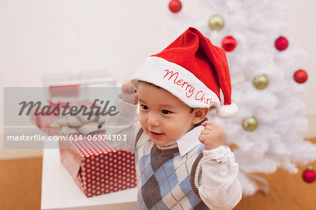 Boy wearing Santa hat in front of Christmas decorations