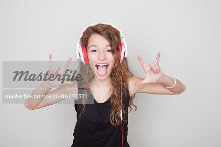 Girl wearing headphones making devil signs and sticking tongue out