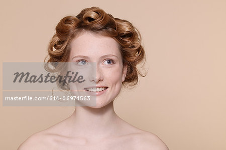 Young woman with curly red hair looking away and smiling