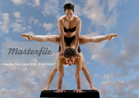 Mid adult dancers balancing on top of each other against blue sky