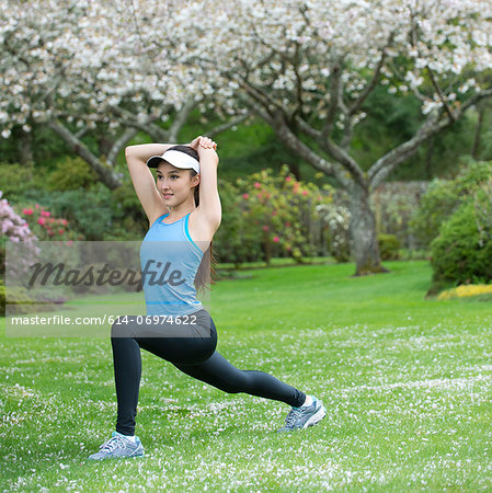 Teenage girl wearing blue sportswear stretching in park
